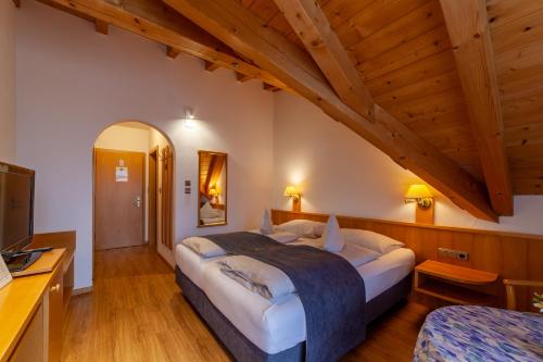 Un dormitorio con una cama grande en una habitación con techos de madera. en Frühstücks-Hotel Olympia, en Tirolo