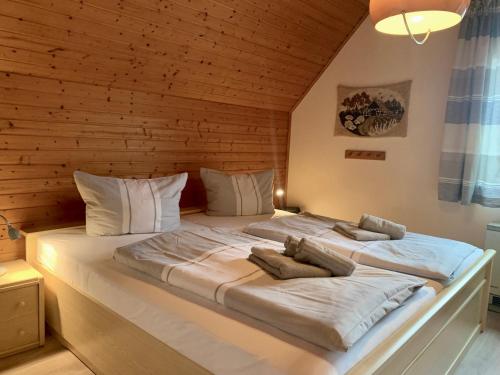 - un grand lit dans une chambre dotée d'un mur en bois dans l'établissement Ferienwohnung "Ostergeest", à Sankt Peter-Ording