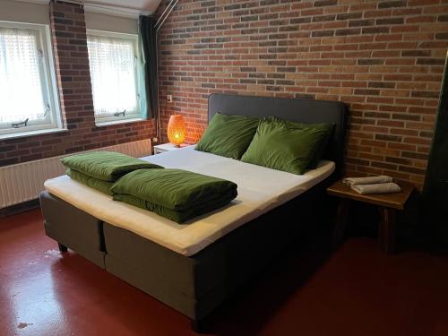 a bedroom with a bed with green pillows and a brick wall at Familiehuis in Diever