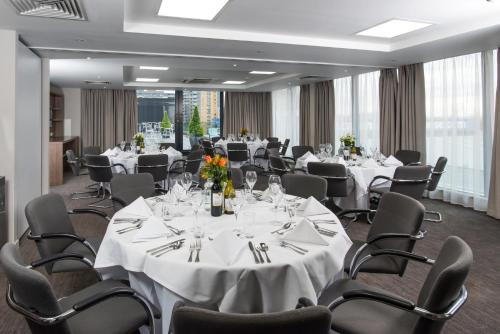 une salle de conférence avec des tables et des chaises blanches dans l'établissement Holiday Inn London West, an IHG Hotel, à Londres