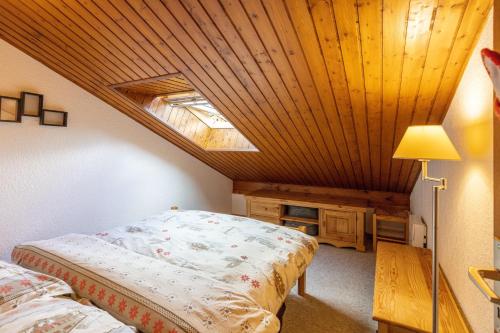 une chambre avec un lit et un plafond en bois dans l'établissement Le Forchat - proche des pistes, à Bellevaux