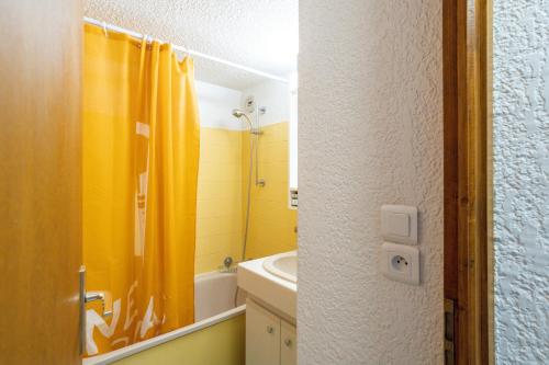 baño con cortina de ducha amarilla y lavamanos en Le Forchat - proche des pistes, en Bellevaux