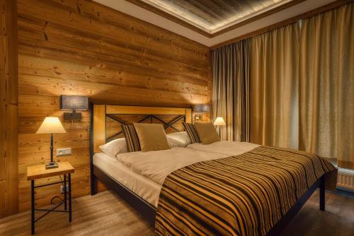 a bedroom with a bed and a wooden wall at Apartmán Jelení Grúň Jasná in Belá