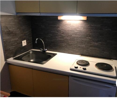 une cuisine avec un évier et une cuisinière dans l'établissement La montagne « un coin d’oxygène », à Châtel