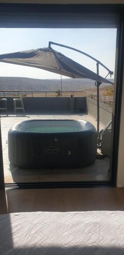 a hot tub in a room with an umbrella at נס הבריאה in Midreshet Ben Gurion