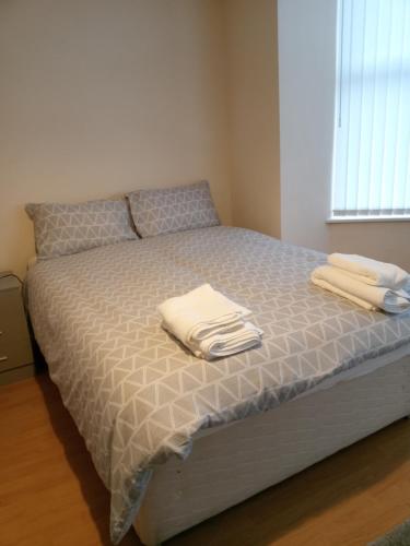 a bed with two white towels on top of it at Sandringham House in Liverpool