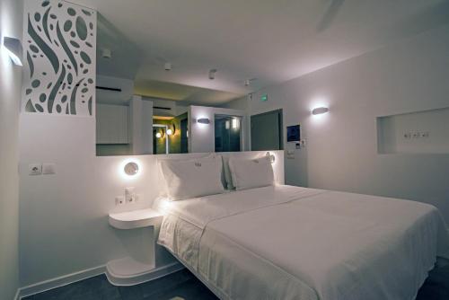 a white bedroom with a bed and a mirror at Makrikythera Luxury Suites - Private Pool or Hot Tub Suites in Dhiakofti
