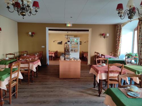a dining room with tables and chairs and a kitchen at Hôtel Saint-Georges in Saint-Jean-de-Maurienne