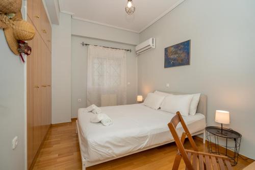 a bedroom with a white bed and a wooden floor at Renovated Lovely Apt next to Marina Flisvos in Athens