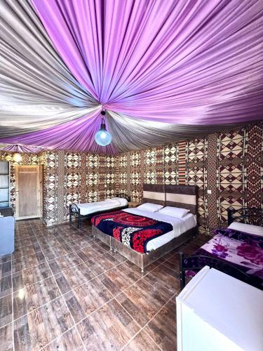 a bedroom with two beds and a purple ceiling at Hasan Zawaideh Camp in Wadi Rum