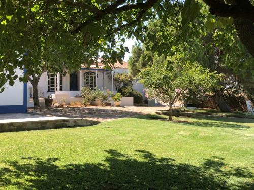 a yard with green grass and trees in front of a house at Vale de Camelos Country House, Alentejo, Portugal. in Alcaria Ruiva