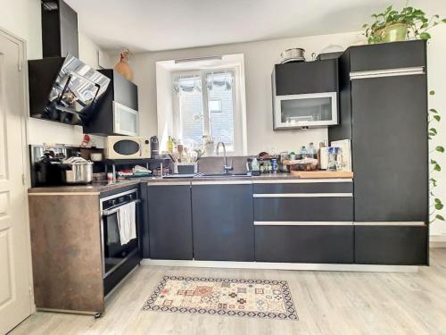 - une cuisine avec des placards noirs et un évier dans l'établissement Location Granville - Remparts de la Hauteville, à Granville