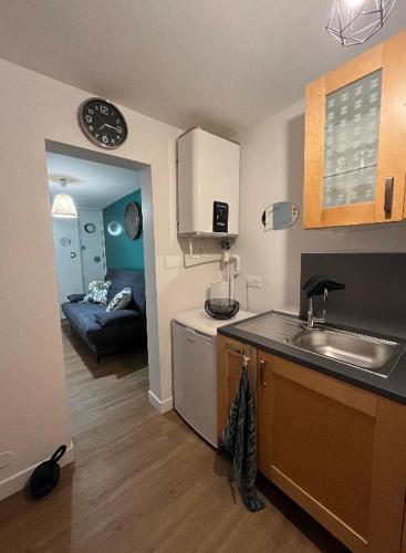 une cuisine avec un évier et un canapé dans une chambre dans l'établissement Adorable F1, au bord du lac d’élancourt village, à Élancourt