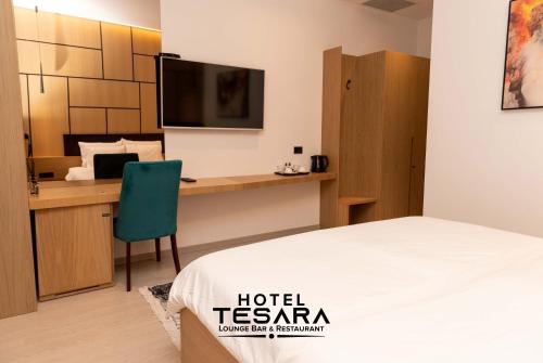 a room with a bed and a desk with a television at Hotel Tesara in Prizren