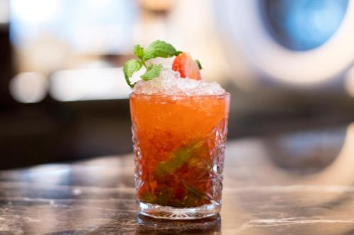 a drink with a strawberry and ice on a table at SANA Malhoa Hotel in Lisbon