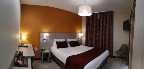 a hotel room with a large bed and a desk at Hôtel Saint-Georges in Saint-Jean-de-Maurienne