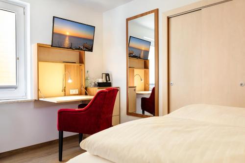 a bedroom with a bed and a red chair and a mirror at Helgolandia Dependance in Helgoland