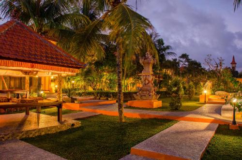 a resort with a palm tree and a fountain at Green Field Hotel and Restaurant in Ubud