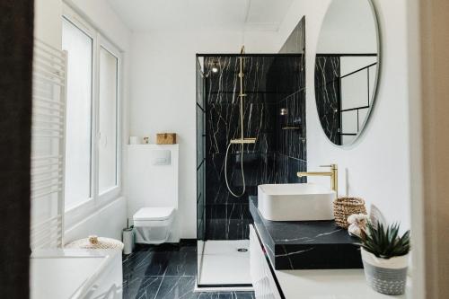 - une salle de bains en noir et blanc avec lavabo et miroir dans l'établissement L'Alma16:Jardin, centre ville, belles prestations, à Cherbourg en Cotentin