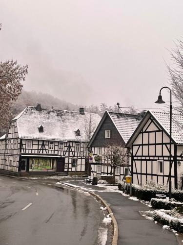 two black and white buildings with snow on the ground at Gästehaus Sille in Morsbach - Holpe in Morsbach