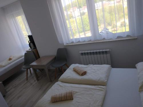 a bedroom with two beds and a desk and windows at Dom Gościnny Bożenka in Niechorze