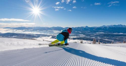a man is skiing down a snow covered slope at Apartment Deluxe Ossiacher See - Gerlitzen in Sattendorf