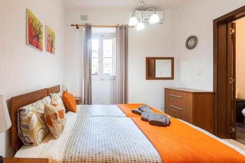 a bedroom with a large bed with an orange blanket at Superbly Located Cosy 2-Bedroom Apartment Valletta in Valletta