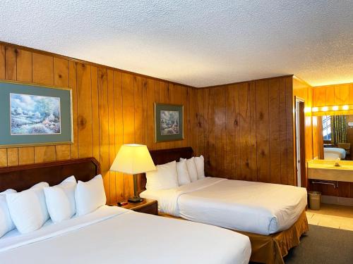 two beds in a hotel room with wooden walls at Traveler's Inn in Eureka Springs