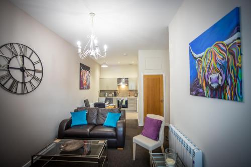 a living room with a couch and a clock at Douglas House Apartments in Nairn
