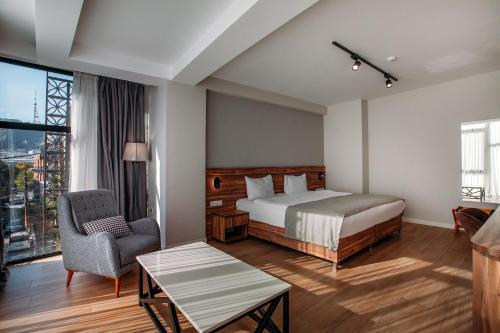 une chambre d'hôtel avec un lit et une chaise dans l'établissement Address Boutique Hotel, à Tbilissi