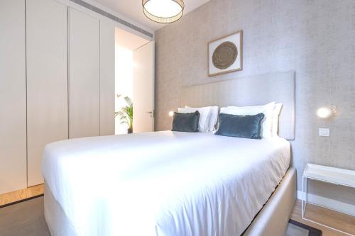 a bedroom with a large white bed with blue pillows at Ando Living - Douradores House in Lisbon