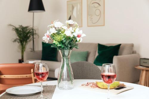 un jarrón de flores en una mesa con dos copas de vino en Ando Living - Douradores Townhouse, en Lisboa