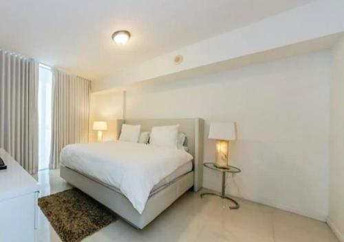 een witte slaapkamer met een groot bed en een lamp bij Luxurious 1BR Condo At Icon Brickell in Miami