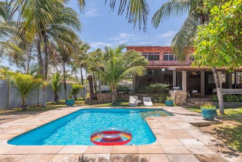a swimming pool in front of a house with palm trees at Casa Dunas - Espaço e Conforto em PDD by Carpediem in Aquiraz