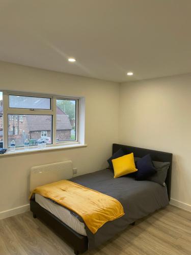 um quarto com uma cama com almofadas amarelas e azuis em London Studios in BR54LT em Saint Mary Cray
