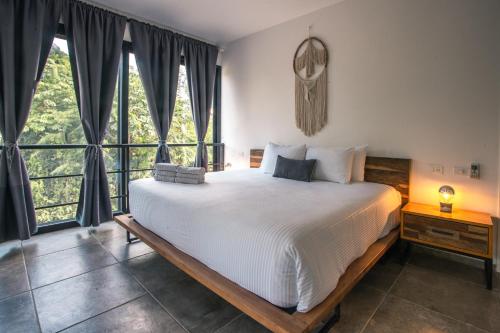 a bedroom with a large bed and large windows at Panacea Condo Tulum in Tulum