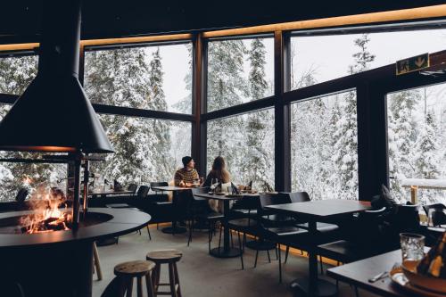 un restaurante con gente sentada en mesas frente a las ventanas en Magical Pond Nature Igloos, en Ruka