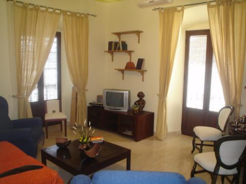 a living room with a blue couch and a tv at Apartamentos De Turismo Rural Heredero in Burguillos del Cerro