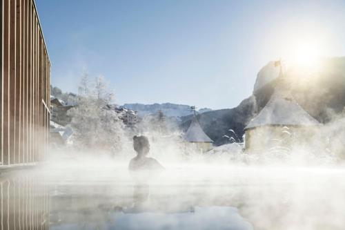 a woman sitting in a hot tub in the middle of a steam bath at Adler Spa Resort Dolomiti in Ortisei