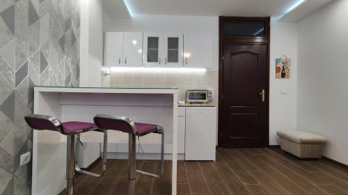Apartman Vivaldi - CENTAR في Vrnjačka Banja: مطبخ مع اثنين من المقاعد الأرجوانية في مكتب