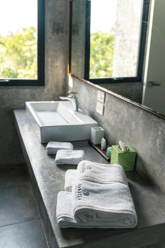 a bathroom with a sink and towels on a counter at Panacea Condo Tulum in Tulum