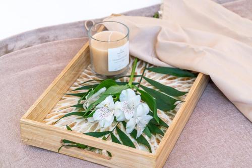 a wooden tray with a candle and flowers on a bed at Encant de Alaior Boutique Hotel in Alaior