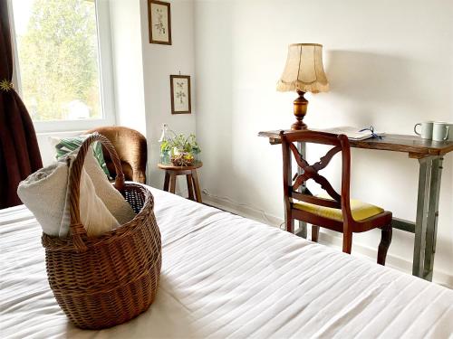 un cesto su un letto con tavolo e sedia di L'Autre Rivière - Chambres d'hôtes a Ducey