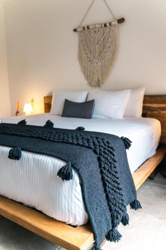 a bed with a blue and white blanket on it at Panacea Condo Tulum in Tulum