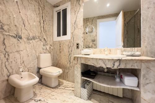 een badkamer met een toilet, een wastafel en een spiegel bij ApartEasy - Passeig de Gracia in Barcelona