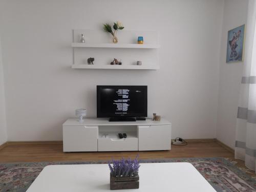 una sala de estar con TV en un centro de entretenimiento blanco en Apartman Deni en Travnik