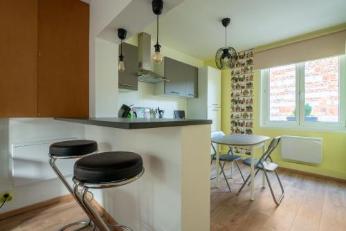 une cuisine avec deux tabourets de bar et un comptoir dans l'établissement Les Potiers 2 - charmant appartement en duplex, à Arras