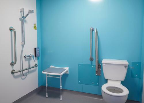 a bathroom with a toilet and a blue wall at Holmfield Arms by Greene King Inns in Wakefield