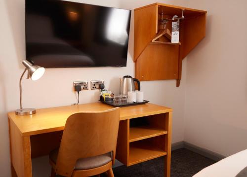 a desk with a chair and a television on a wall at Holmfield Arms by Greene King Inns in Wakefield