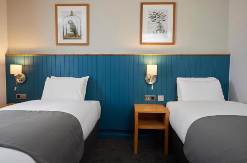 Duas camas num quarto com paredes azuis em Holmfield Arms by Greene King Inns em Wakefield